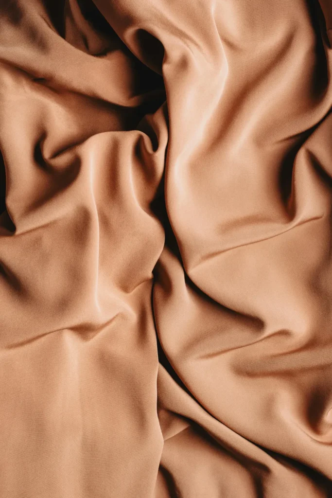 A close-up of a smooth tan silk fabric. a simple wallpaper aesthetic